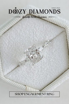 a diamond ring sitting on top of a white cloth in a box with the words dozy diamonds