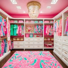 the closet is filled with lots of colorful clothes and pink carpeted flooring, along with chandelier lights