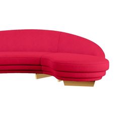 a red curved couch sitting on top of a wooden table