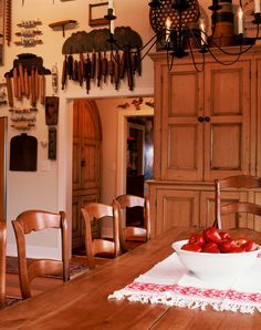 a wooden table topped with a bowl of fruit on top of a wooden dining room table