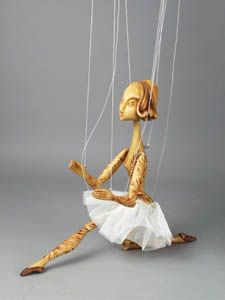 a wooden doll sitting on top of a white sheet with strings hanging from it's legs