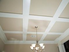 a chandelier hanging from the ceiling in a room with beige walls and white trim