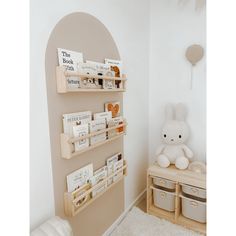 a white teddy bear sitting on top of a wooden shelf next to a book case