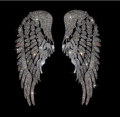 two large white wings with sparkling crystals on them, against a black background in the shape of an angel's wings