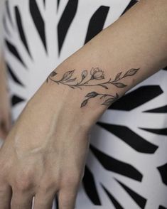 a woman's hand with a small tattoo on her left wrist and the other arm