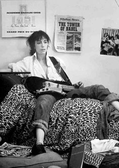 a man sitting on top of a bed holding a guitar