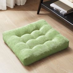 a green square cushion sitting on the floor