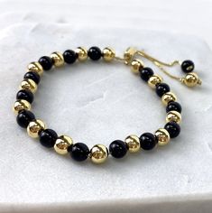 "18k Gold Filled 1mm Box Chain Bracelet Featuring Simulated Onyx Black Bead Ball, Gold Beads, Adjustable Bracelet - Bracelet Size: Thickness: 0.9 mm | Beads Width: 5.8 mm | Length: 9 Inches 💎 With new products daily, quality and competitive prices, in DiJu Jewelry you find the most unique styles of modern designs, always looking for elegance and market trends. *Helping your Jewelry Businesses Grow *Starting your Own Business *Making your Own Collection: DiJu Jewelry ever brings Better Moments f Adjustable Gold Onyx Bracelets, Adjustable Gold Onyx Bracelet, Adjustable Black Bracelets With Gold Beads, Adjustable Yellow Gold Beaded Bracelets With Polished Beads, Gold Beaded Bracelets With Onyx Gemstones, Gold Onyx Beaded Bracelets With Gemstones, Black Bracelets With Spacer Beads As Gift, Black Bracelets With Spacer Beads For Gift, Black Bracelet With Adjustable Chain