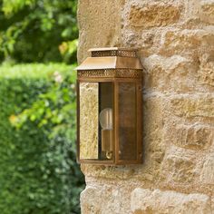 an old fashioned wall light on the side of a stone building with trees in the background