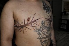 a man has tattoos on his chest and is standing in front of the camera,