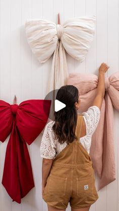 a woman standing in front of two bows hanging on the wall with her hands behind her head