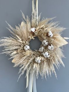 a dried wreath hanging on the side of a wall next to a white ribbon and some cotton balls