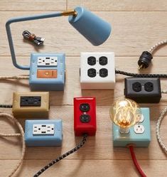 many different electrical plugs and wires on a wooden floor with a lamp in the middle