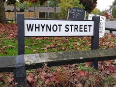 a sign that is on the side of a wooden fence in front of a street