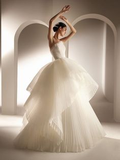 a woman in a white dress is posing for the camera with her arms up and hands behind her head