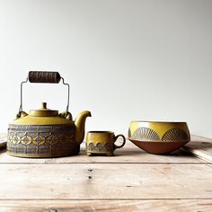 a tea pot and two cups on a wooden table