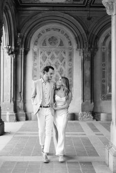 a man and woman walking through an old building