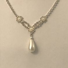 a white necklace with pearls and beads on a mannequin neckline, hanging from a silver chain