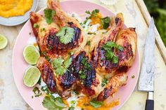 a pink plate topped with chicken covered in cilantro sauce and garnishes