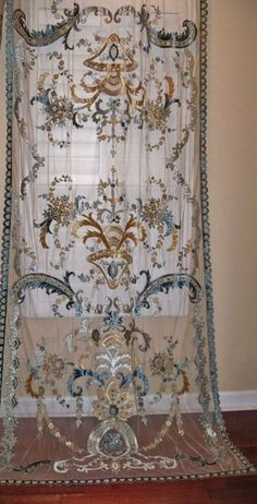 the curtain is hanging on the wall in front of the window and has an ornate design