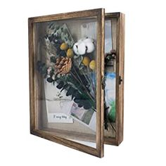 an old wooden frame with flowers and pine cones in it on a white background for display