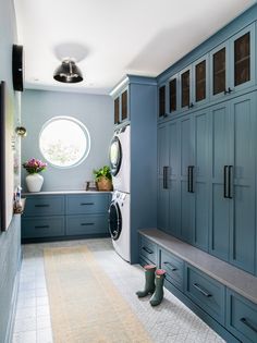 a washer and dryer in a laundry room with blue cabinets, an arched window, and a bench