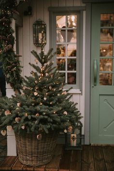 a small christmas tree in a basket on the porch