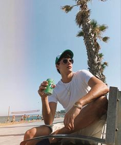 a man sitting on the back of a pickup truck holding a green cup and looking at the camera