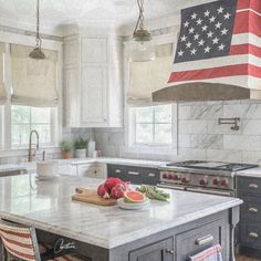 an american flag hanging from the ceiling in a kitchen with marble counter tops and island