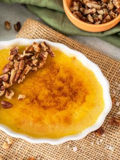 a white bowl filled with food on top of a burlied table cloth next to a brown and green napkin