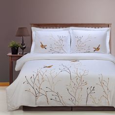 a bed with white comforter and two birds on the tree branch print pillowcase