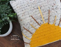 a crocheted sun pillow sitting on top of a wooden table next to a potted plant