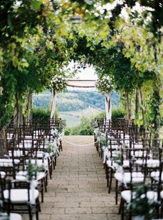 an outdoor ceremony set up with chairs and greenery