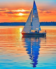 a sailboat is sailing on the water at sunset