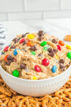 a white bowl filled with cereal and m & m's on top of pretzels