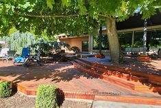 an outdoor deck with steps and chairs under a tree