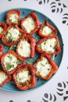 small stuffed peppers with cheese and herbs on a blue plate next to a white doily