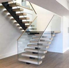 a stair case with glass railing and wooden handrail