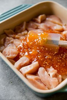 the food in the dish is being cut into pieces with a large knife and sesame seeds sprinkled on top