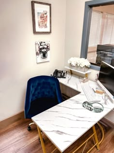 a desk with a computer on it and a blue chair in front of the window