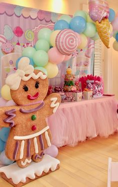 a gingerbread man is standing in front of a table with balloons and other decorations