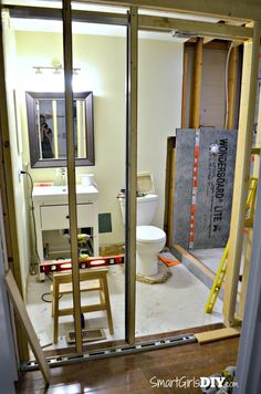 an unfinished bathroom is seen through the glass door