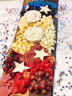 a long tray filled with cheese, fruit and crackers on top of a table