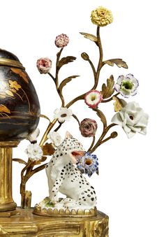 a decorative vase with flowers on it next to a small bird figurine and an egg