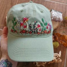 a green hat with embroidered mushrooms on it