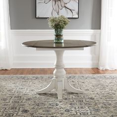 a white table sitting on top of a rug in front of a painting and window