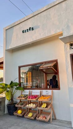 an outside view of a store with fruit on display in the window and behind it is a potted plant