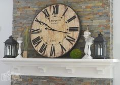 a large clock mounted to the side of a brick wall above a mantel with candles