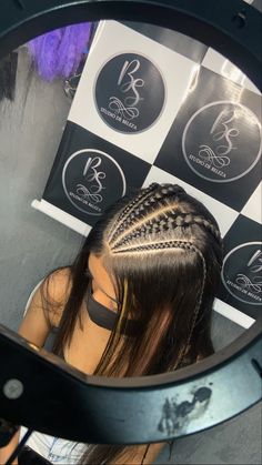 a woman sitting in front of a mirror with her hair styled into a fishtail braid