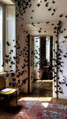 a room filled with lots of black birds flying in the air and on the wall